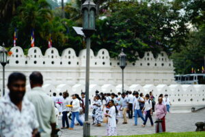 キャンディ仏歯寺の内部で床に伏して熱心に祈る白い服の参拝者たち