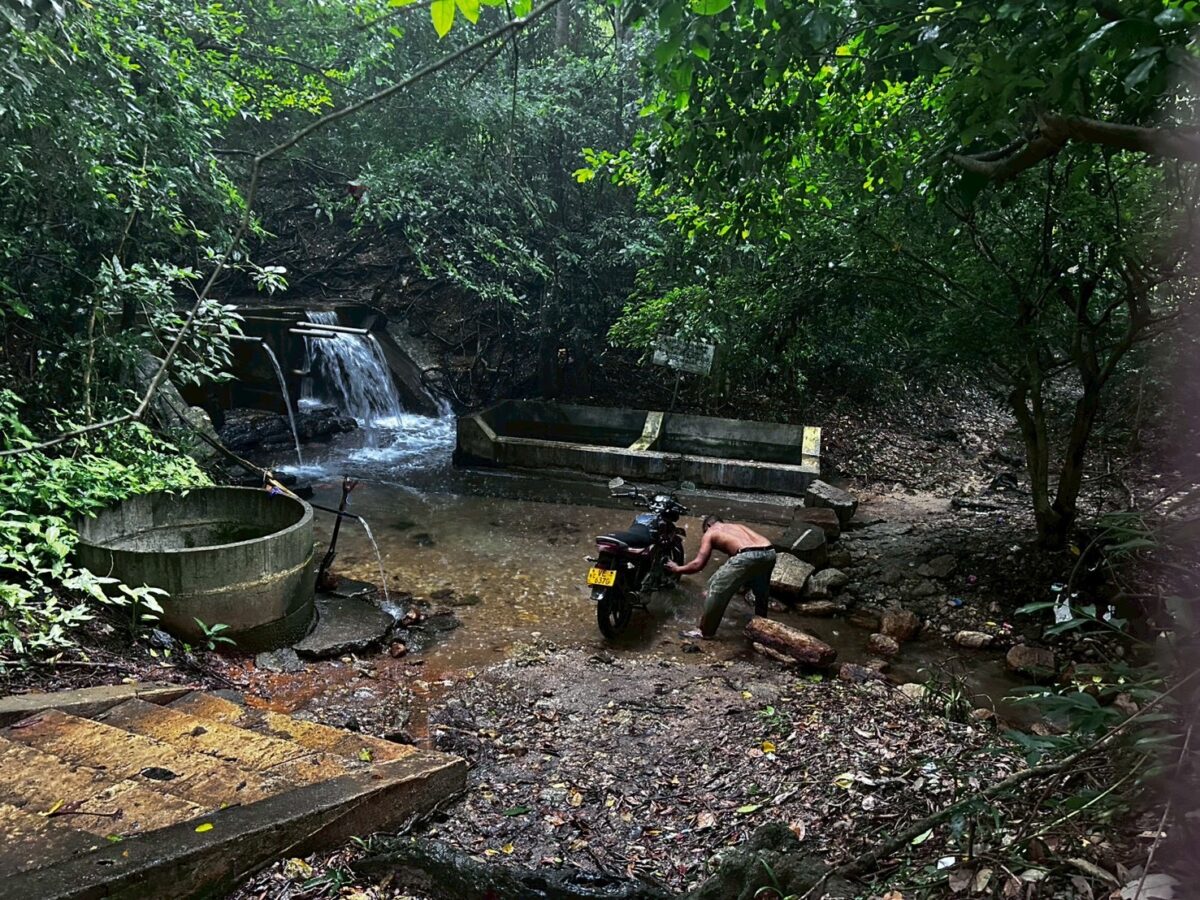 シギリヤの川の中でバイクを洗車する地元男性