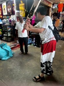 キャンディの市場で陽気にクリケットの打ち方を教えるスリランカ人のおじさん